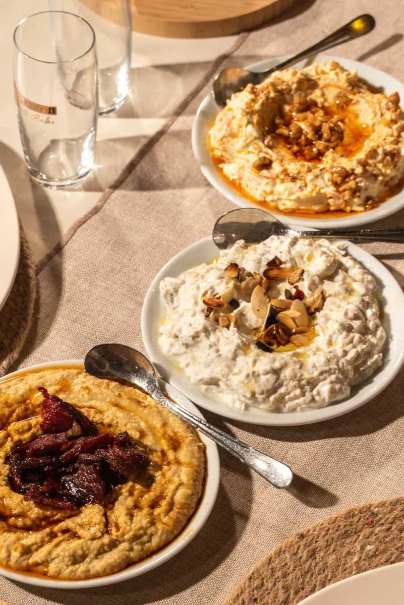 Beyaz tabaklarda üç meze: pastırmalı humus, badem dilimli haydari ve zeytinyağlı ezme